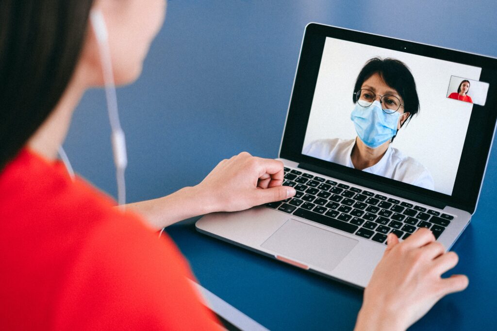 woman sitting looking at a laptop talking to a healthcare practitioner about the abortion pill