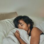 A young woman in bed with period or pregnancy symptoms