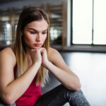 Woman in pink top looking at the ground with her hands folded