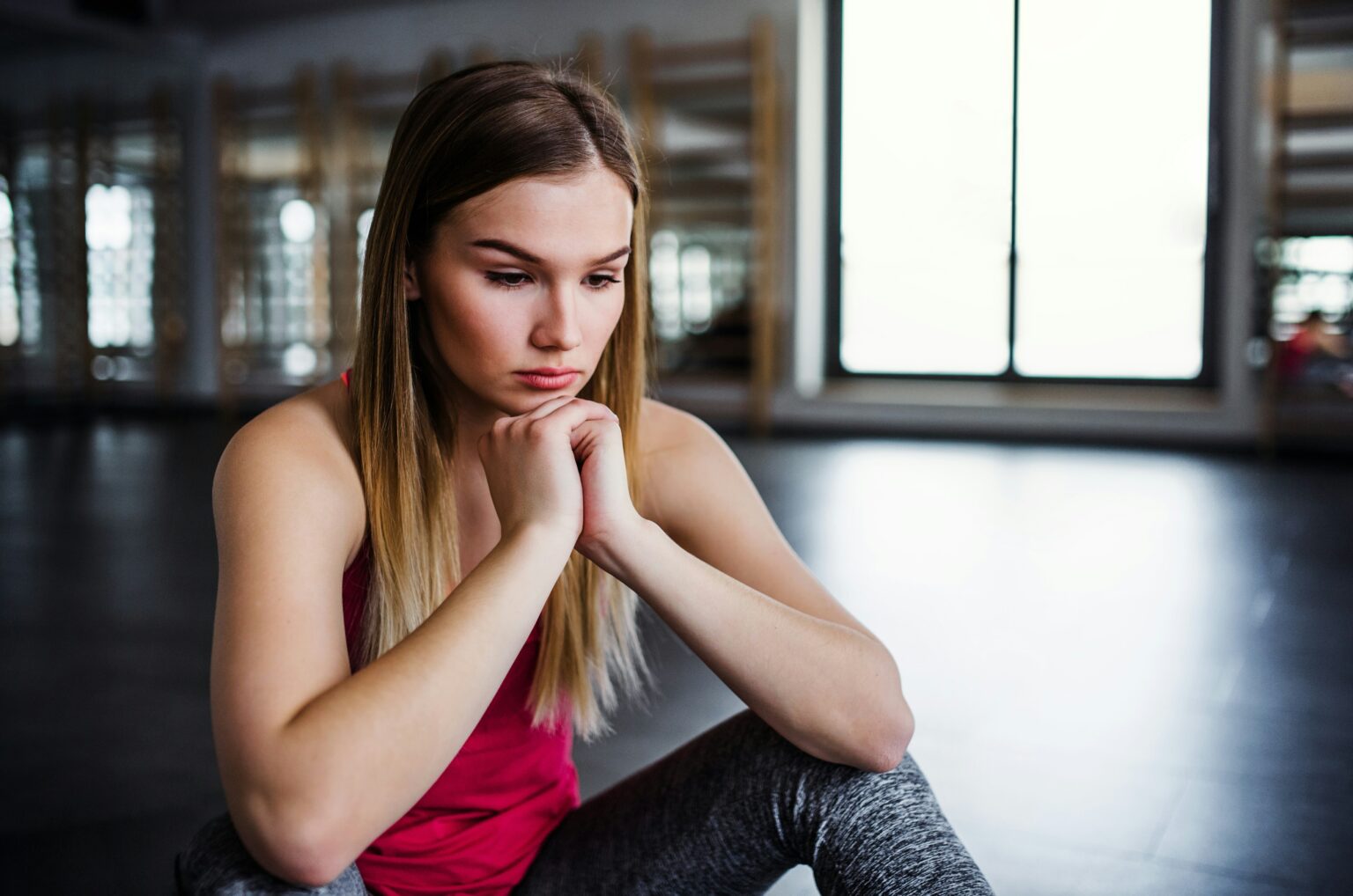 Woman in pink top looking at the ground with her hands folded