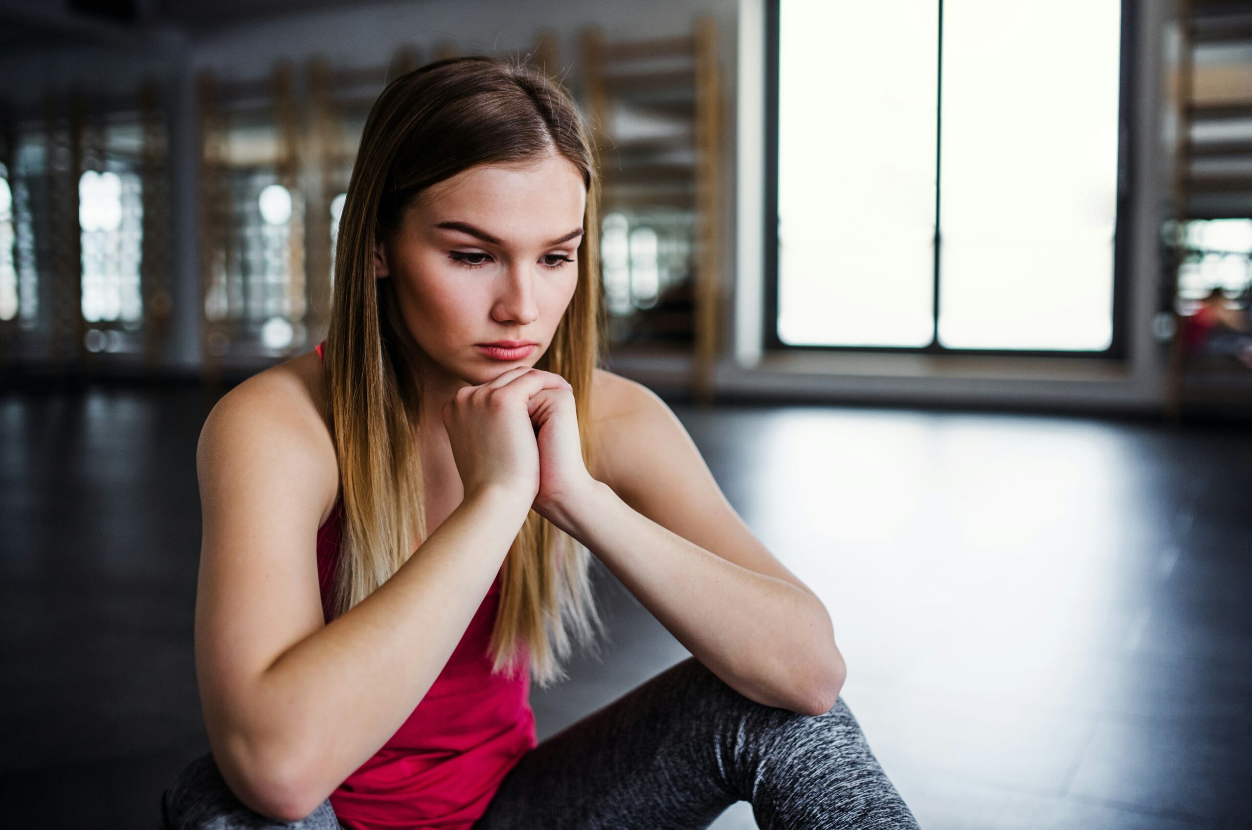 Woman in pink top looking at the ground with her hands folded