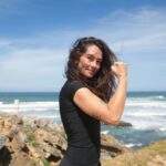 women smiling at beach flexing arm