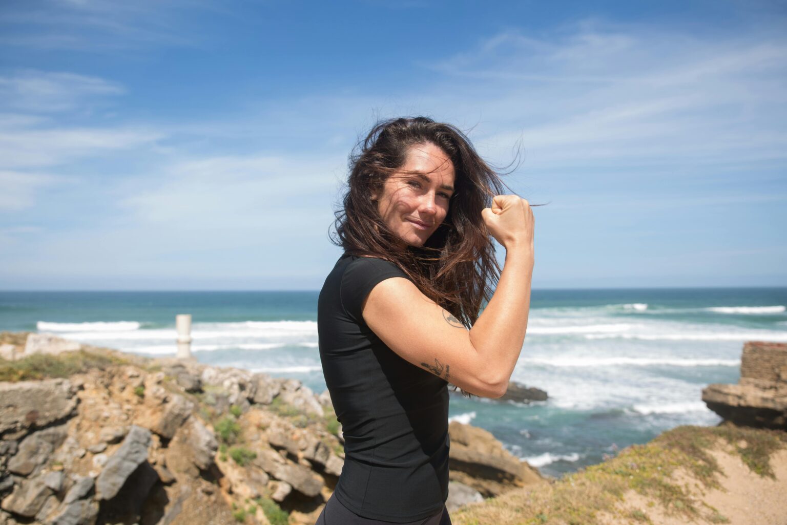 women smiling at beach flexing arm