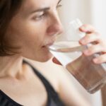 Woman in black tank top drinking water
