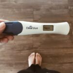 girl holding white and blue pregnancy test that says pregnant